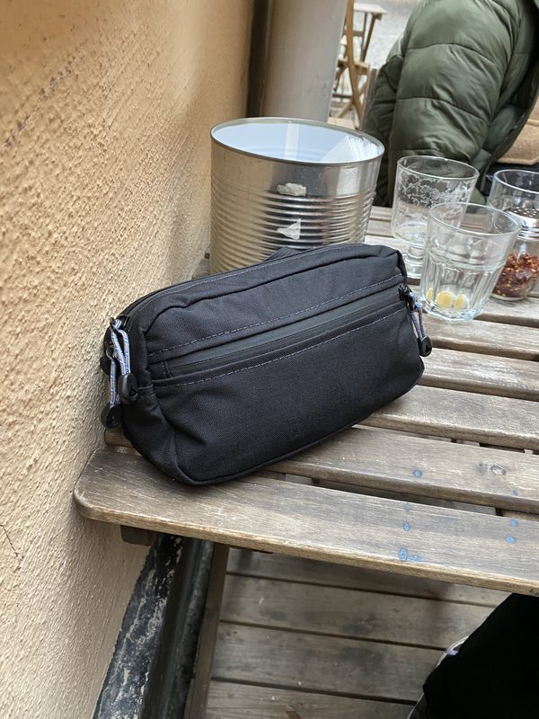A small black zippered bag resting on a wooden café table.